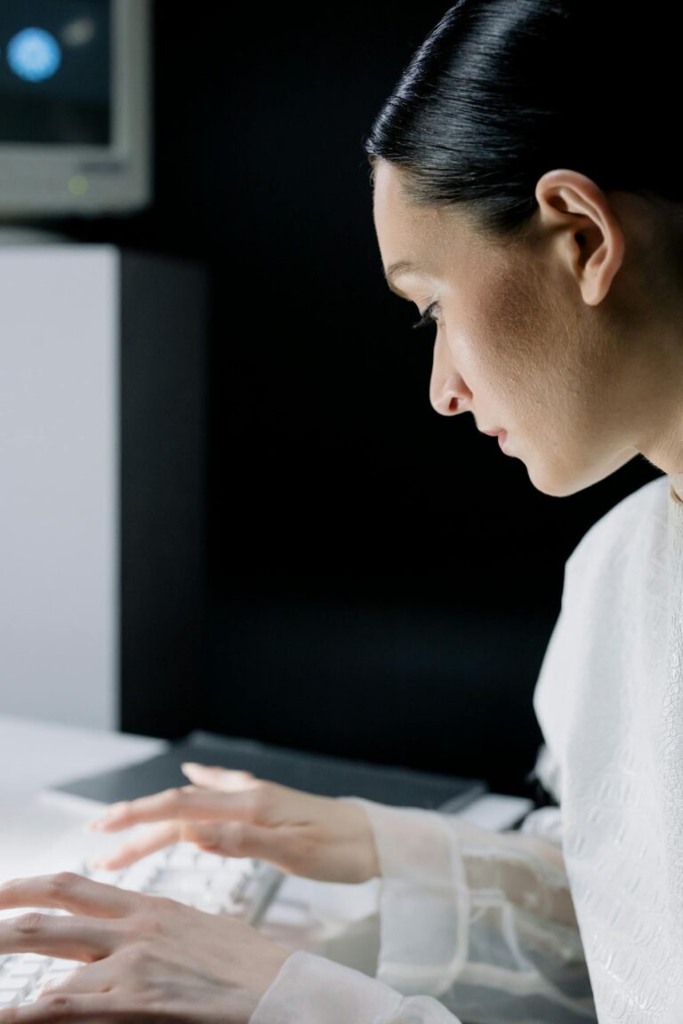 A concentrated female scientist types on a keyboard, working in a laboratory setting.