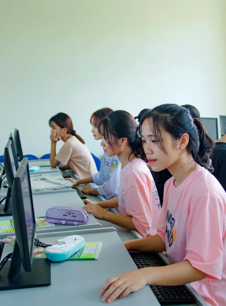 A group of young students focused on computer tasks in a modern classroom setting.
