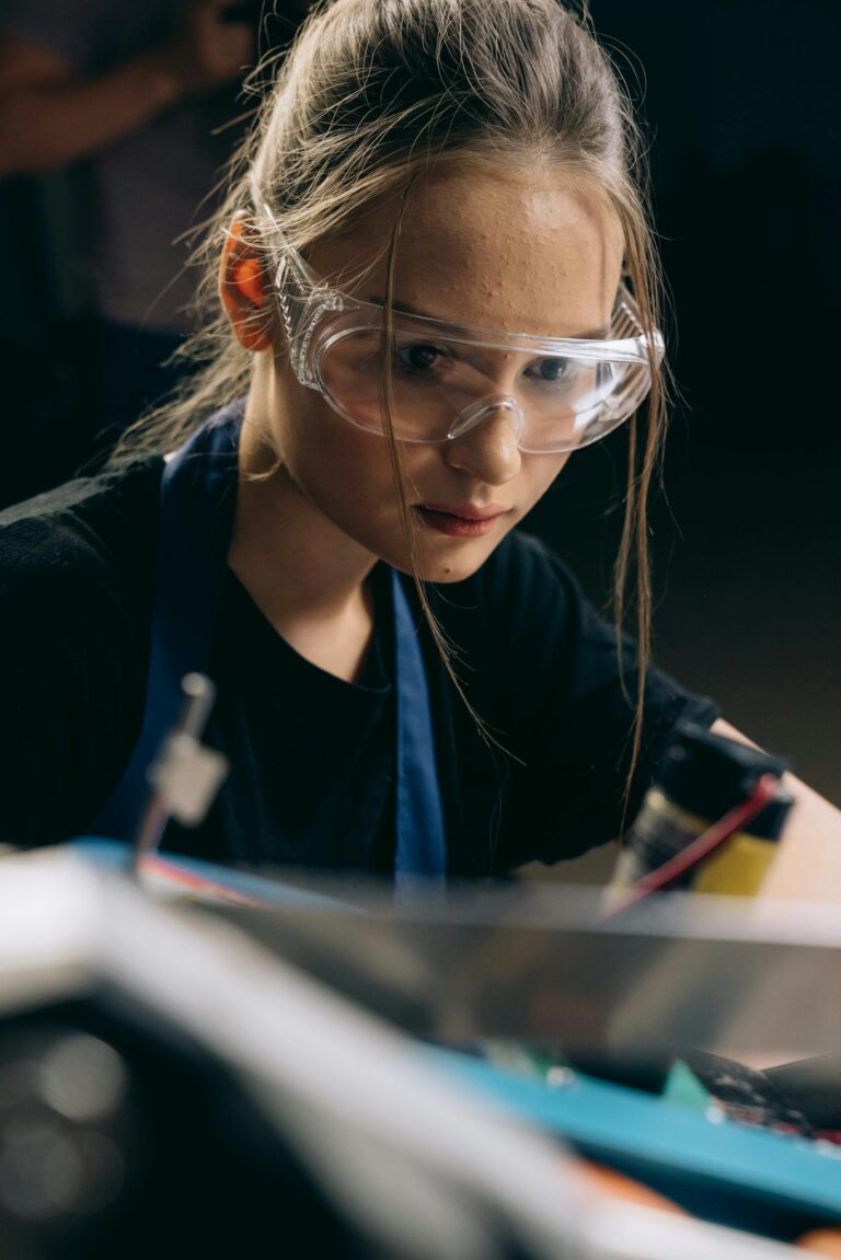 Focused young female engineer wearing safety glasses working on a project.